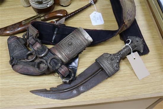 An Omani khanjar in decorative white metal-mounted wooden scabbard on woven belt and two other items,